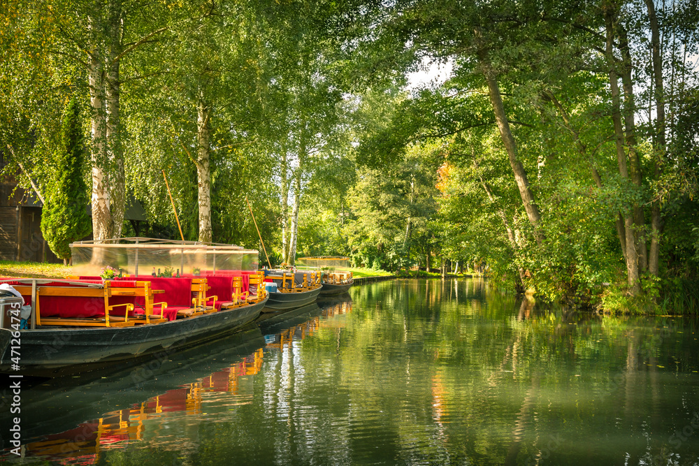 Ausflugsschiffe im Spreewald an einem Kanal mit Spiegelung der Bäume im Wasser