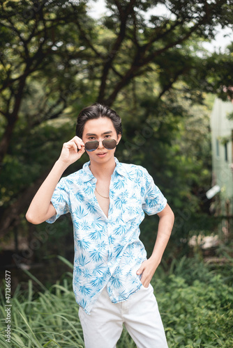 A young man putting down his shades ogling at someone. Noticing a pretty lady passing by.