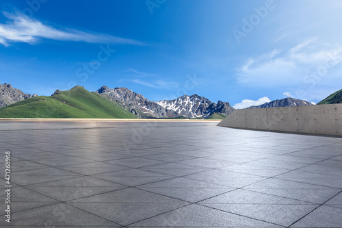 Empty square floor and mountains under blue sky. Road and mountain background.