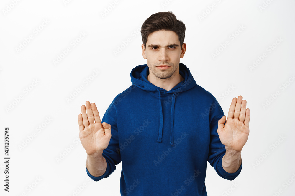 Stop this. Serious concerned man showing block, taboo gesture, say no, prohibit smth, raising palms up to restrain, forbid, standing over white background Stop this. Serious concerned man showing block, taboo gesture, say no, prohibit smth, raising palms up to restrain, forbid, standing over white background