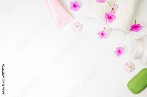 Delicate background, intimate hygiene gel, white towels and a container with pink flowers for aromatherapy.