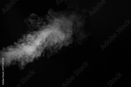 White vapor spray steam from air saturator. Smoke fragments on a black background. Abstract background