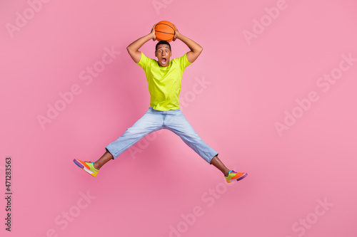 Full body photo of funny millennial guy jump with ball wear vest t-shirt jeans sneakers isolated on pink background