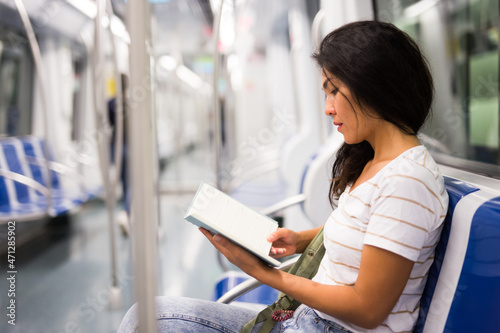  woman reading book while sitting on bench in metropolitan train. © JackF