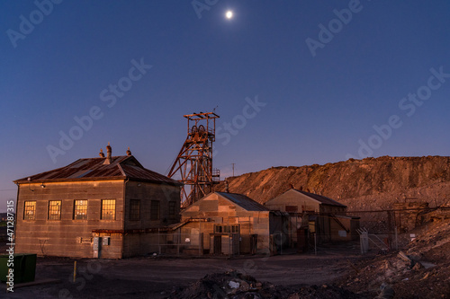 Abandoned sheds and poppet head in a mining landscape under full moon