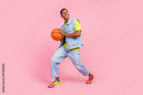 Full size photo of funny millennial brunet guy play basketball wear t-shirt vest jeans footwear isolated over pink color background