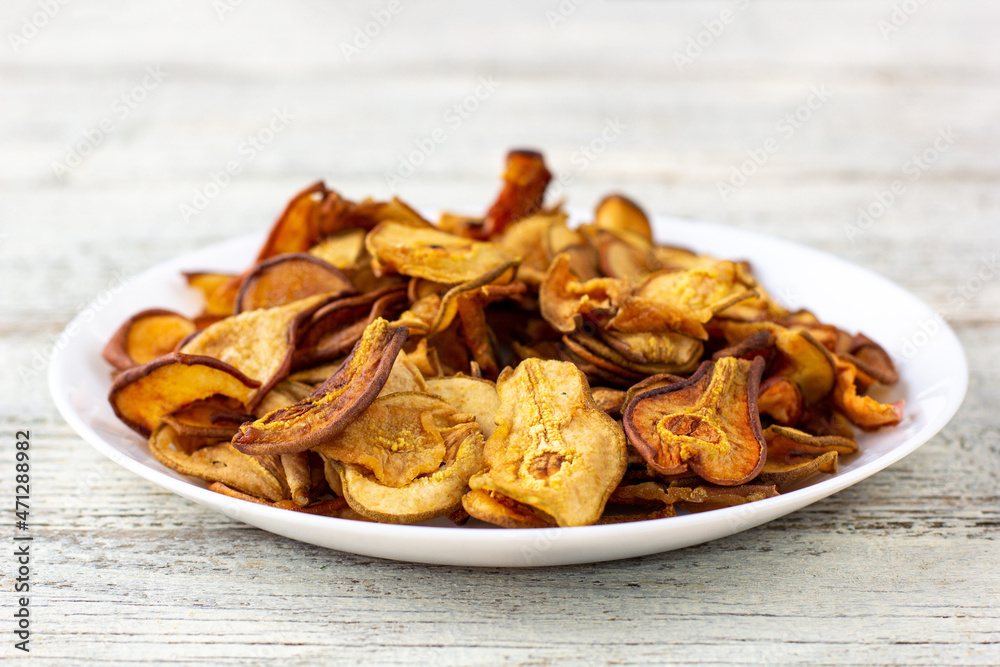 A pile of dried pears in slices on a white plate on wooden background. Dried fruit chips. Healthy food A pile of dried pears in slices on a white plate on wooden background. Dried fruit chips. Healthy food