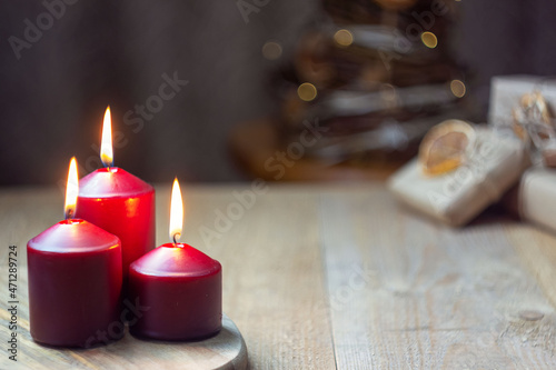 Magic Christmas. three red burning candles, christmas tree and gifts.