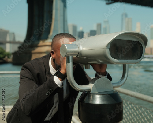 USA, New York City, Man in suit looking at city through coin operated binoculars