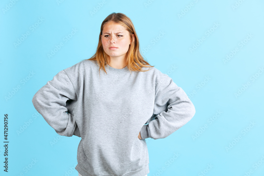 Portrait of young beautiful girl in warm winter clothes, gray sweater isolated on navy color studio background in neon light. Portrait of young beautiful girl in warm winter clothes, gray sweater isolated on navy color studio background in neon light.