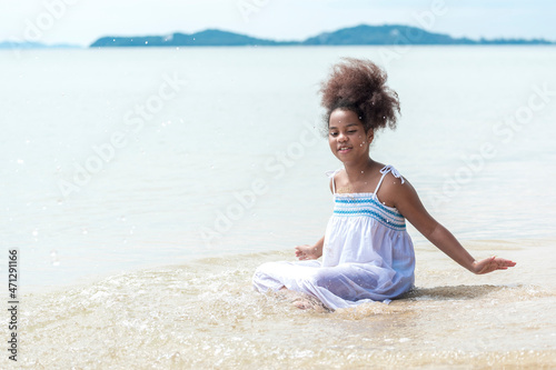 happy african american Little girl sitting and play on the beach