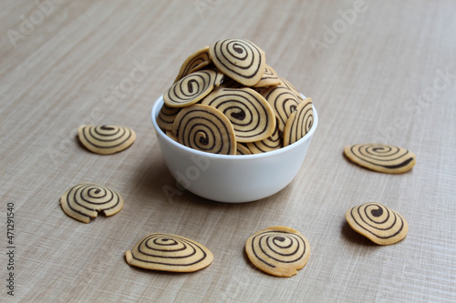 Kue Kuping Gajah, traditional cookies from Indonesia. Sweet and crunchy, unique spiral pattern. Wooden background.