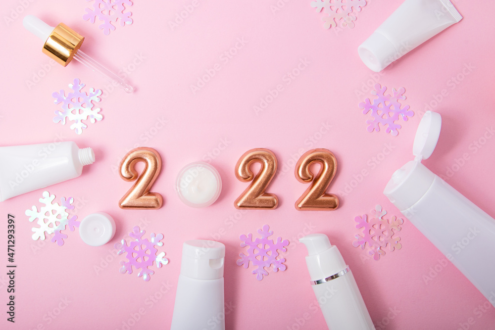 Top view of the cosmetics containers on pink background.Rose gold numbers 2022 above.Good for new year offer and text overlay. Top view of the cosmetics containers on pink background.Rose gold numbers 2022 above.Good for new year offer and text overlay.