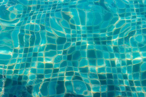 Abstract defocused background with turquoise water in swimming pool. Rippled water with sun reflection in swimming pool. Top view