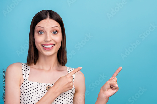 Photo of young excited girl indicate fingers empty space recommend suggest discount isolated over blue color background