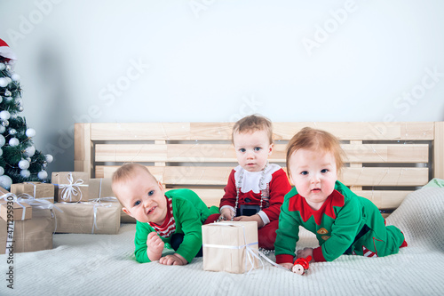 Children dressed as Santa Claus and Elves with Christmas gifts. Baby in suits for New Year..