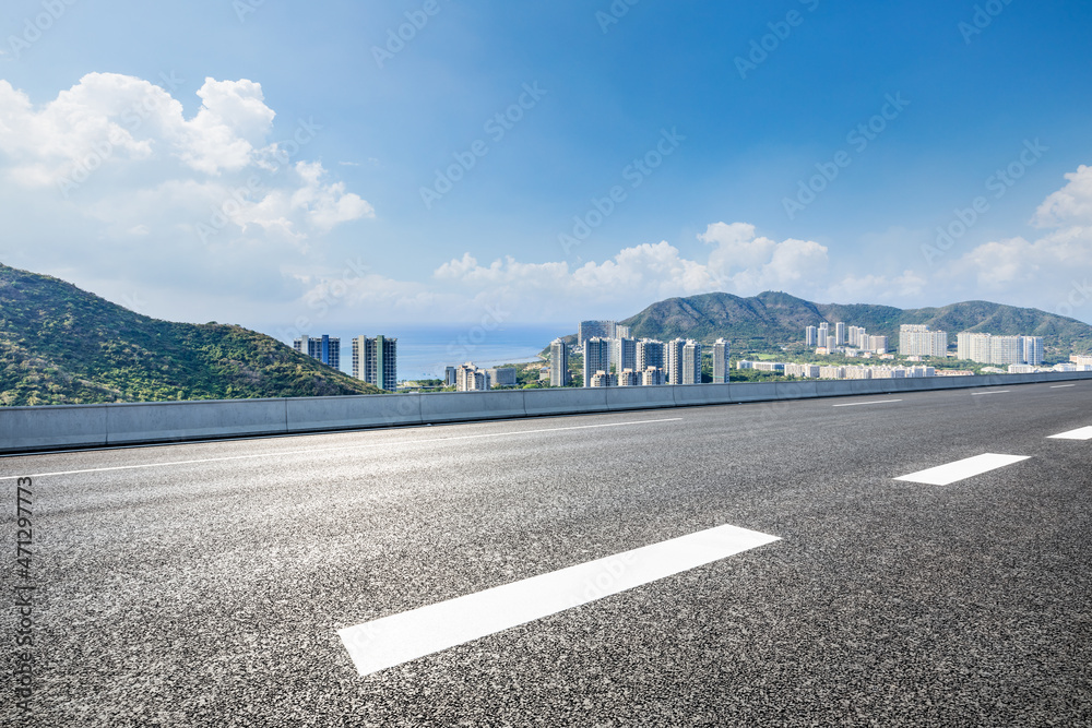 Naklejka premium Asphalt road and modern city commercial buildings with skyline by the sea