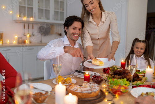 Young woman offering traditional pie to her husband  celebrating Christmas or Thanksgiving with daughter at home