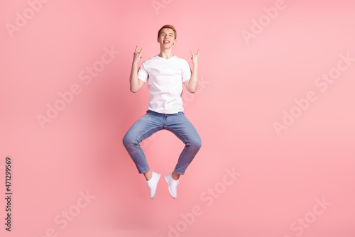 Full length photo of young excited man rejoice victory success fists hands jump isolated over pink color background