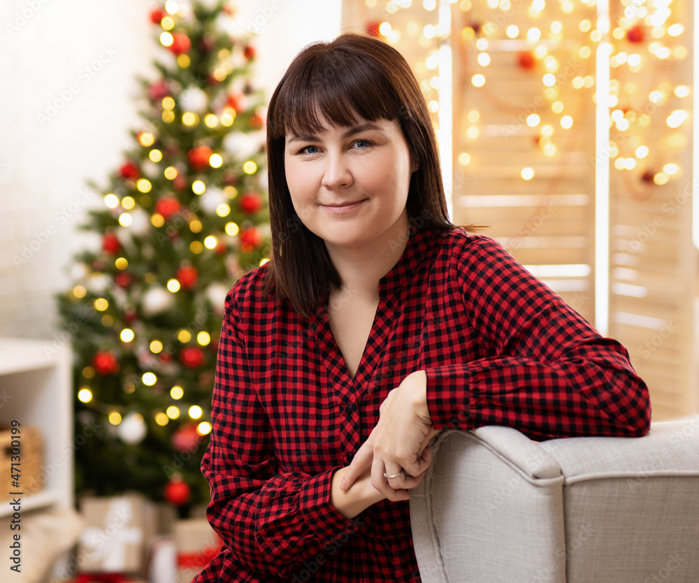Woman sitting in bright decorated living room with Christmas tree Woman sitting in bright decorated living room with Christmas tree