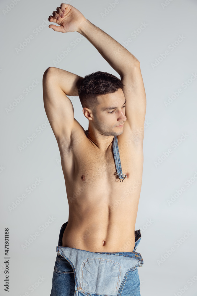 Portrait of young handsome sportive shirtless man in jeans posing isolated on gray studio background. Portrait of young handsome sportive shirtless man in jeans posing isolated on gray studio background.