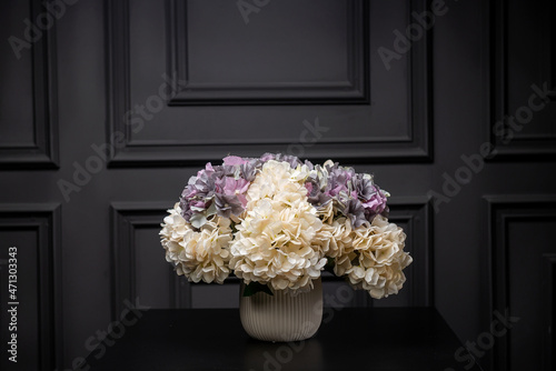 Plastic handmade bouquet artificial flowers composition.Beautiful flowers in vase on a table with black  background. Women's, mother's day. Spring, summer season. Front view.Selective focus.
