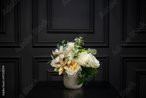 Plastic handmade bouquet artificial flowers composition.Beautiful flowers in vase on a table with black  background. Women's, mother's day. Spring, summer season. Front view.Selective focus.
