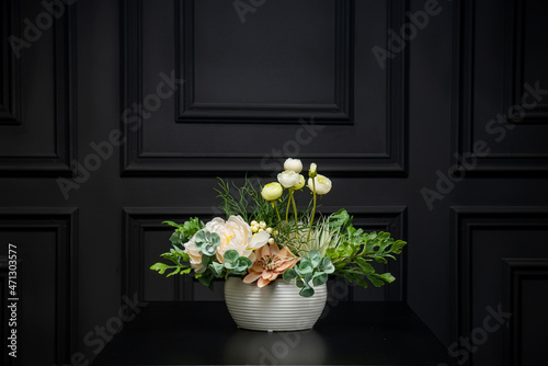 Plastic handmade bouquet artificial flowers composition.Beautiful flowers in vase on a table with black  background. Women's, mother's day. Spring, summer season. Front view.Selective focus.
