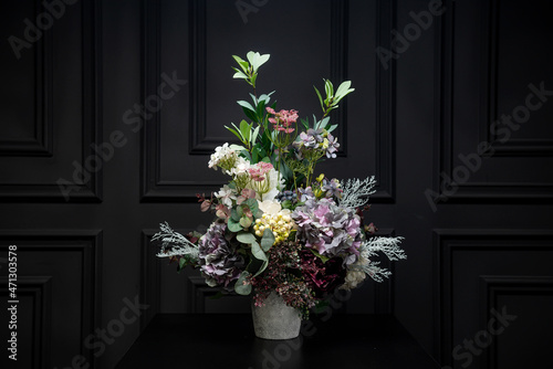 Plastic handmade bouquet artificial flowers composition.Beautiful flowers in vase on a table with black  background. Women s  mother s day. Spring  summer season. Front view.Selective focus. 