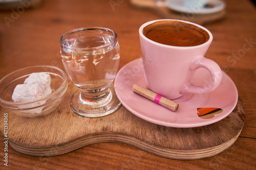  Cup of Traditional delicious Turkish coffee with glass of water and Turkish delight on the table.Cup of coffee in the morning on wooden table with fortune letter.Romantic date in cafe with coffee.