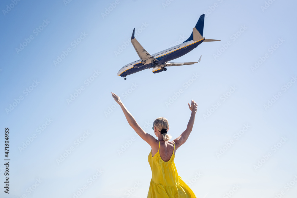 Happy woman with hands up on a blue sky background with real airplane flying over her head. Happy woman with hands up on a blue sky background with real airplane flying over her head.