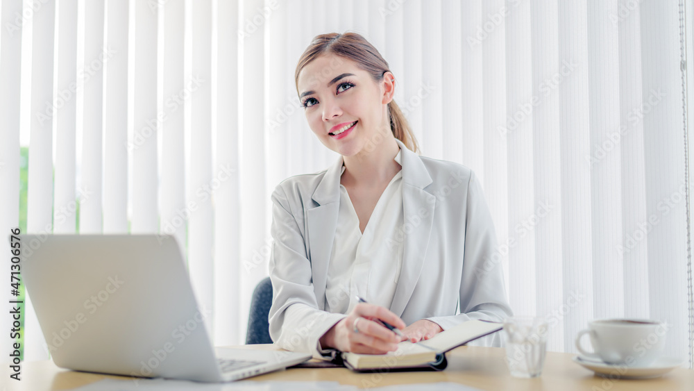 Happy attractive asian business woman smiling working with laptop in modern office Happy attractive asian business woman smiling working with laptop in modern office