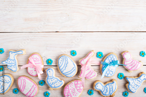 Homemade Easter cookies in shape of eggs chicken and rabbit on white wooden kitchen table flat lay view. Space for text