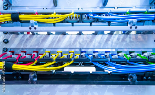 Server rack with blue and red internet patch cord cables connected to black patch panel in data server room