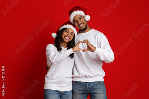 Beautiful black couple celebrating New Year together, red studio background © Prostock-studio