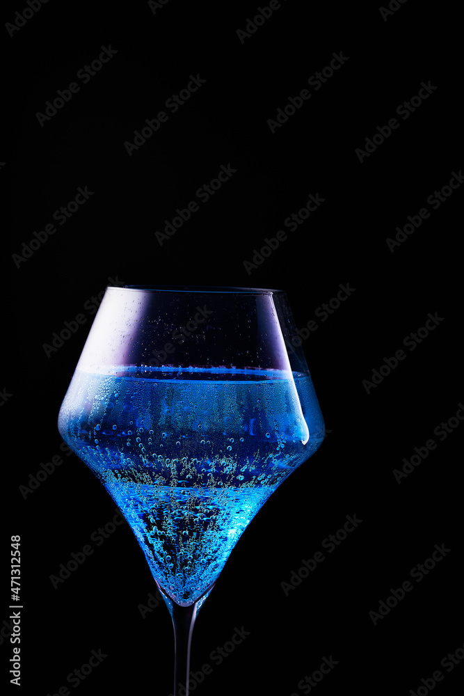 Blue drink is poured into a glass. Black background. Blue drink is poured into a glass. Black background.