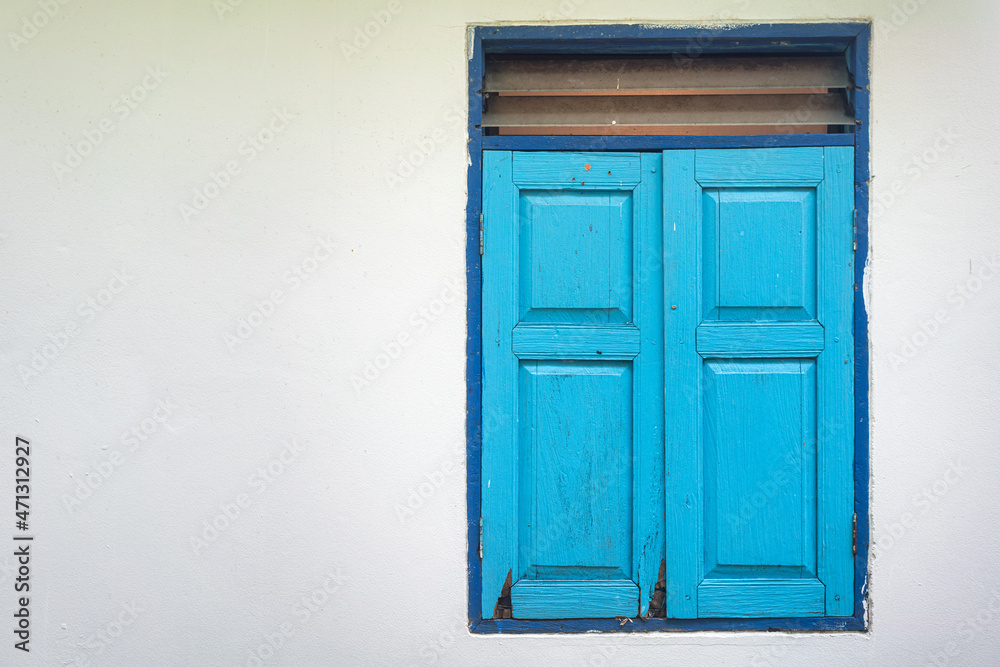 Pastel colorful blue wooden window frame on cement white wall wite space area. Building exterior design and object photo.