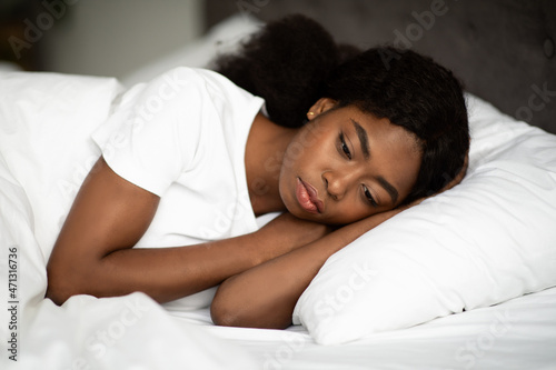 Upset african american lady laying in bed alone
