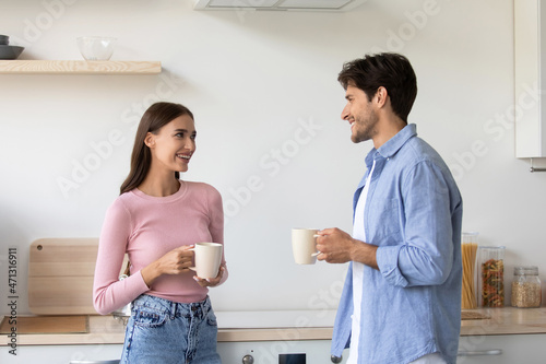 Cheerful millennial european lady and man with cups, communicating and drink coffee in morning