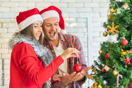 couple Decorating the Christmas tree at home happily, joyfully, smiling. concept Love