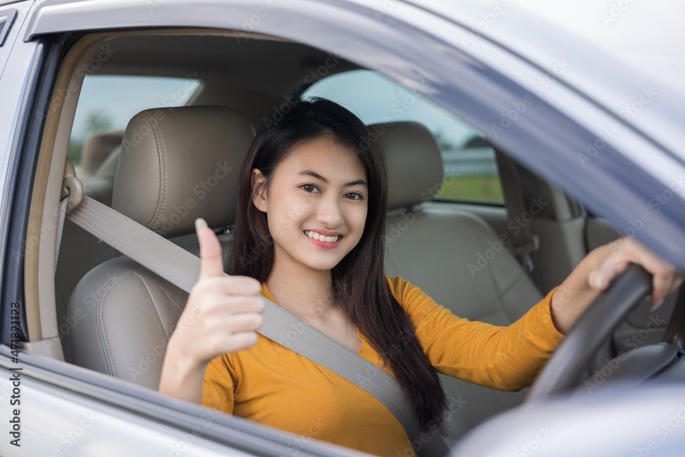 Wow. Young beautiful asian women getting new car. she very happy and excited. she sit and touching every detail of car. Smiling female driving vehicle on the road showing thumb up