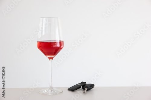 Drinking and driving concept shot. Tall wine glass with Rosé wine next to nondescript car key. Studio shot, no people