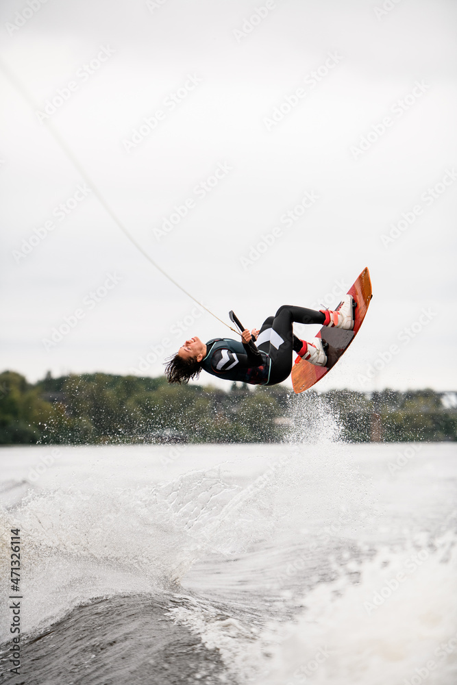 sportive woman jumping and flipping over the water on wakeboard