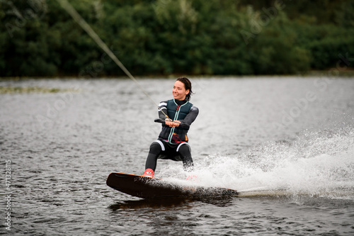 sportive woman wakeboarding on board on the river water on summer day