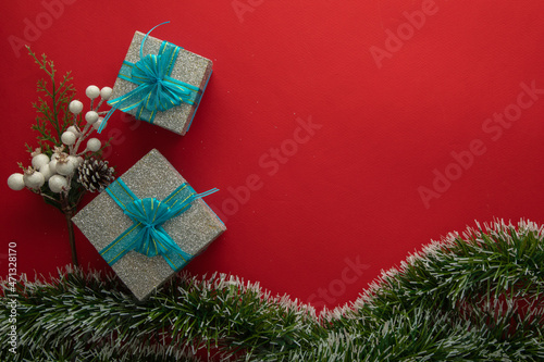 Christmas background with gift boxes with blue bow  green branches and red background