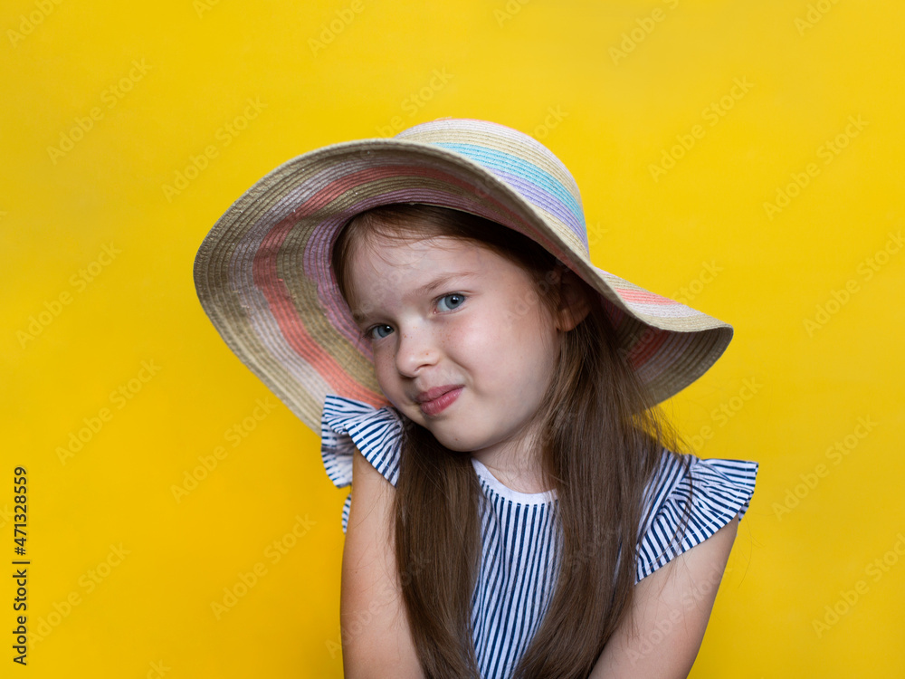portrait of a cute smiling little girl in a hat on a yellow background