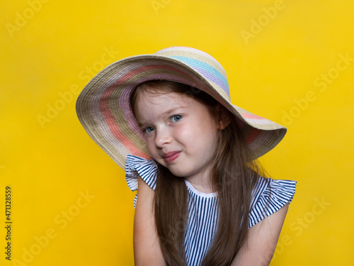 Obraz na płótnie portrait of a cute smiling little girl in a hat on a yellow background w salonie