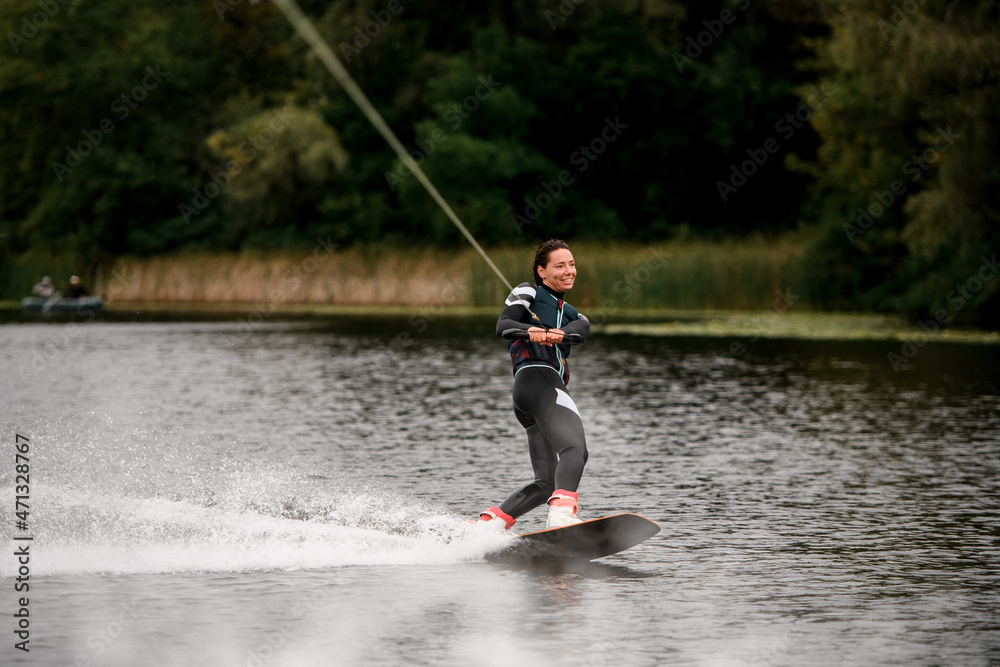 cheerful female wakeboarder riding on wakeboard on river water cheerful female wakeboarder riding on wakeboard on river water