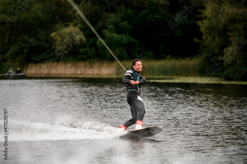 cheerful female wakeboarder riding on wakeboard on river water