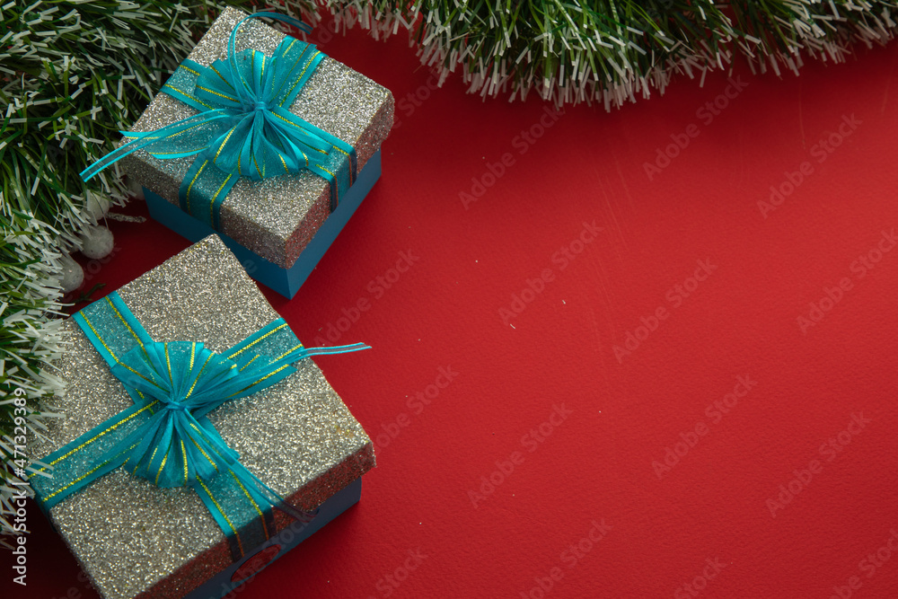 Christmas background with gift boxes with blue bow, green branches and red background Christmas background with gift boxes with blue bow, green branches and red background